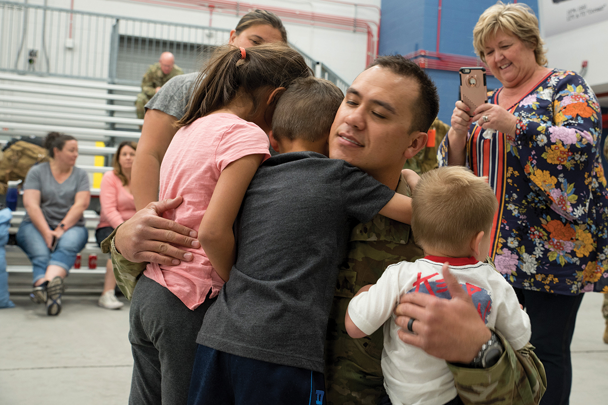 Military father hugging children